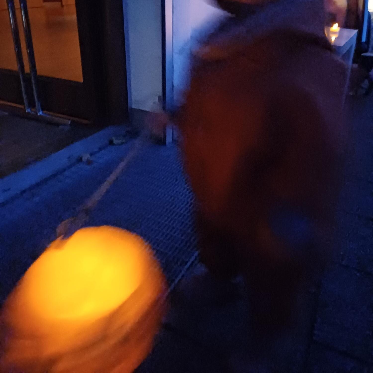 Ein warm gekleidetes Kind hält nachts draußen eine leuchtende Laterne. Das Bild ist unscharf und vermittelt ein Gefühl der Bewegung und eine warme, festliche Atmosphäre.