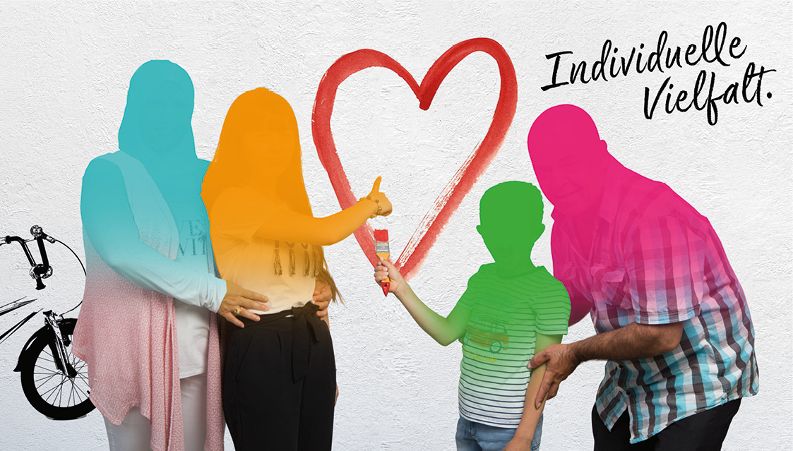 Vier Personen mit verdeckten Gesichtern stehen vor einer weißen Wand, auf die ein rotes Herz gemalt ist. Ein Kind und ein Erwachsener berühren das Herz. Auf der Wand stehen die Worte Individuelle Vielfalt. Auf der linken Seite ist teilweise ein Fahrrad zu sehen.