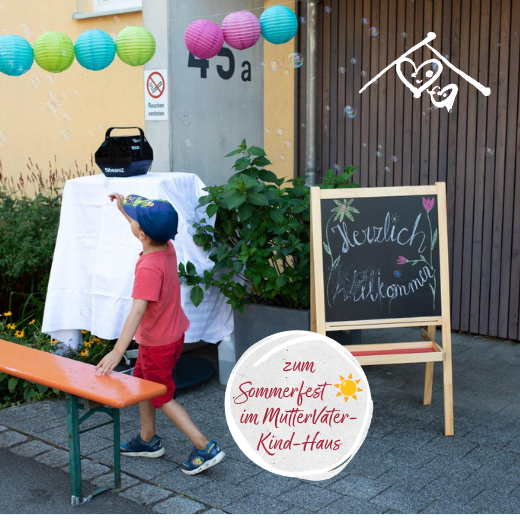 Ein kleines Kind mit einer Mütze greift bei einem Sommerfest nach Seifenblasen. Über ihm hängen bunte Papierlaternen, und eine Kreidetafel heißt die Gäste willkommen. Die Szene spielt sich im Freien in der Nähe eines Gebäudes ab, an dem ein geschmücktes Schild für die Veranstaltung angebracht ist. Weibliche Inspiration. Stark für Frauen. Stark für Menschen.